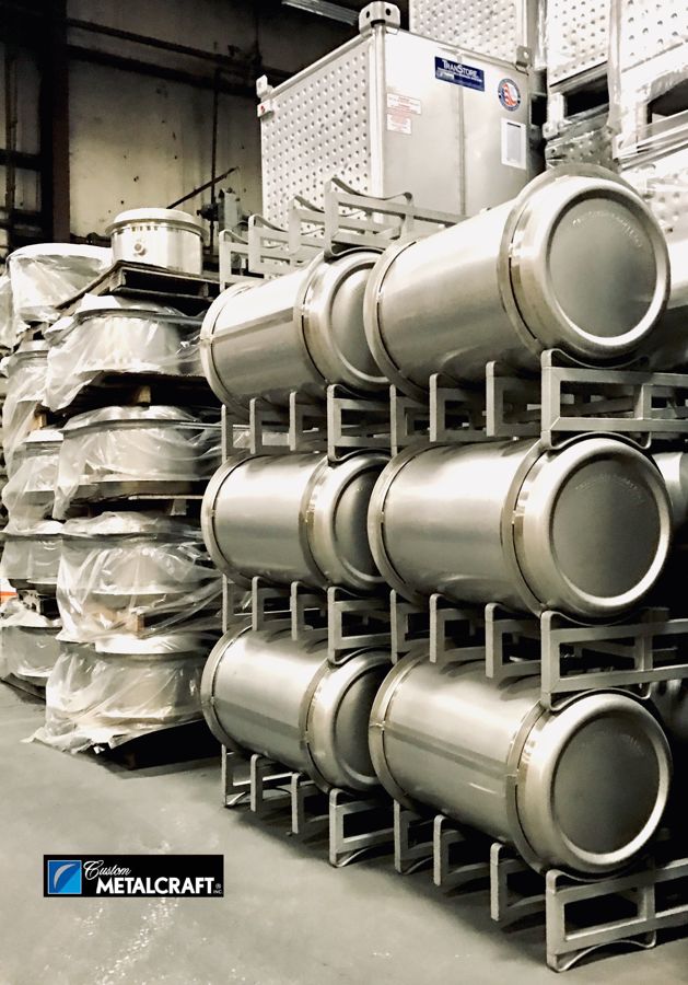 Custom Metalcraft stainless steel barrels stacked on racks with a TranStore tank behind them