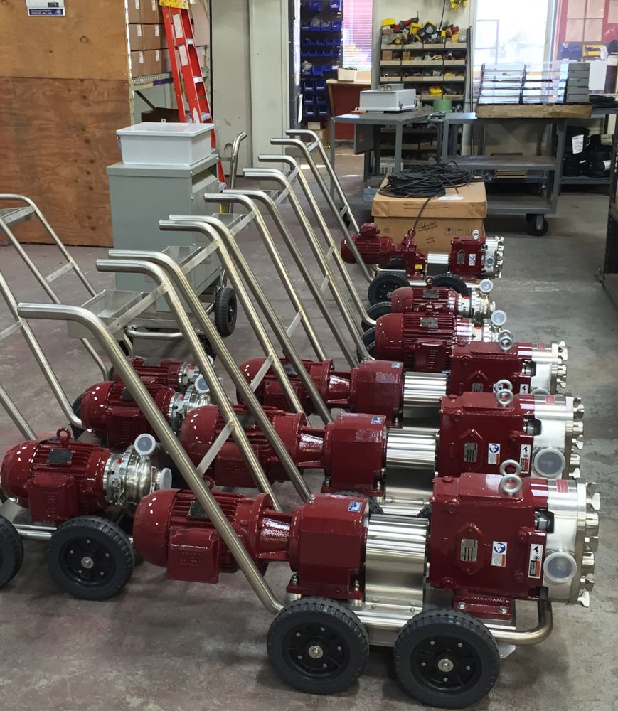 A row of Waukesha-type Carlsen positive displacement pumps on stainless carts